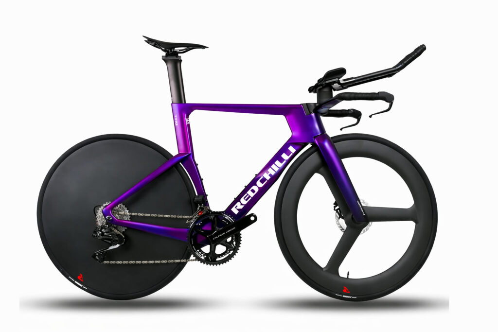 COMPLETE BIKES: TT & Track Side view of a Redchilli TTR1 time trial bike in a metallic purple finish, featuring an aerodynamic frame, integrated aero cockpit, rear disc wheel, deep-section tri-spoke front wheel, and disc brakes, displayed against a plain light background.